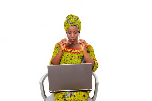 beautiful mature woman sitting in traditional dress on white background wearing glasses with laptop on her thighs.