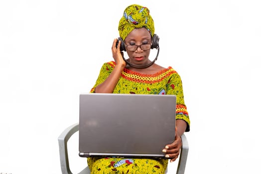 beautiful mature woman in eyeglasses isolated on white background communicating with laptop using headphones.