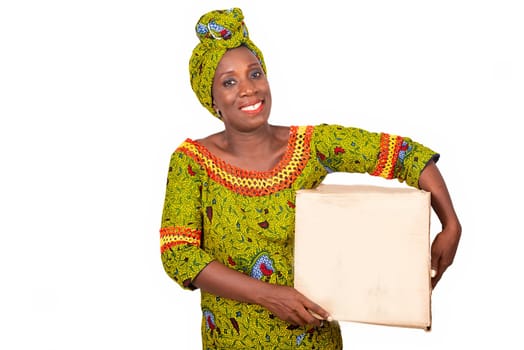 beautiful african adult woman wearing a loincloth and a green scarf, smiling standing holding a cardboard box in her hand