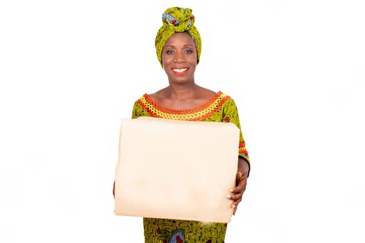 beautiful African adult woman wearing a loincloth and a green scarf in her head, smiling standing holding a cardboard bag