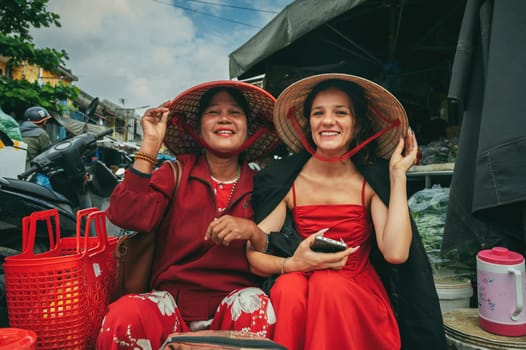 Happy tourist girl with a Vietnamese woman saleswoman at a street food market in Hoi An in Vietnam in Asia. Hoi An, Vietnam - December 2, 2024