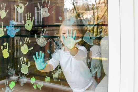 Girl paints with palms on the window. Quarantine Stay at home