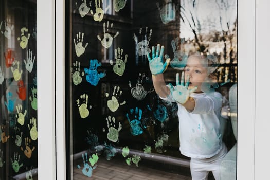 Girl paints with palms on the window. Quarantine Stay at home