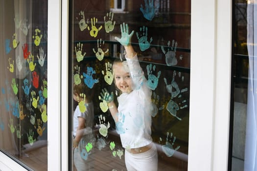Children paint with palms on the window. Quarantine Stay at home