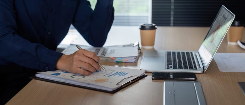 A colleague engages in meticulous note-taking while analyzing financial data in a modern office. The emphasis is on strategic planning and understanding key metrics.