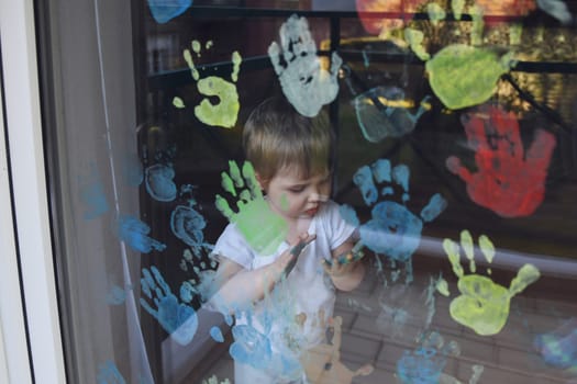 A boy paints with palms on the window. Quarantine Stay at home
