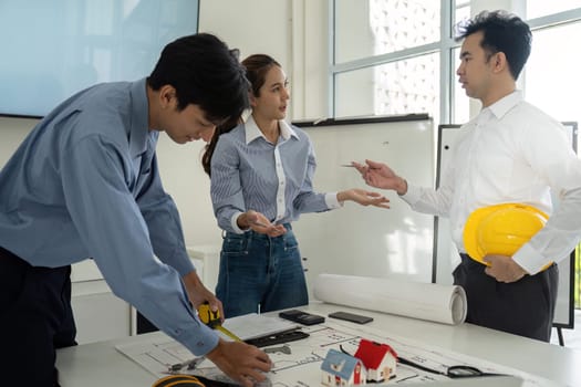 Professionals in construction engage in a discussion while reviewing architectural plans, highlighting collaborative efforts and design solutions.
