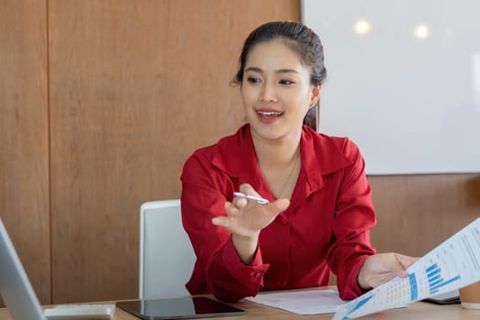 A business professional in a red blazer is discussing financial reports, captivated as she points out important data during a meeting. Perfect for online finance themes.