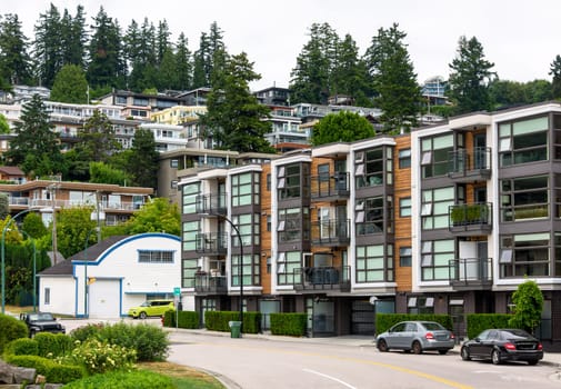 A perfect neighborhood. Uphill residential area with cars parked on the streets around the building.