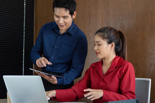A man and woman engage in a collaborative financial discussion, analyzing reports on a tablet and reviewing data to enhance strategic decisions in business.