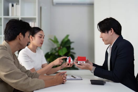 The couple evaluates different properties with their real estate agent, actively discussing features and preferences to find their dream home.