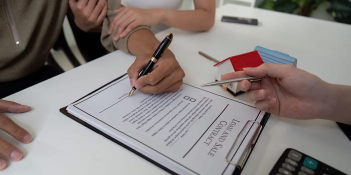 A couple carefully reviews and signs the sales contract with their real estate agent, ensuring all terms are understood in this important home-buying process.