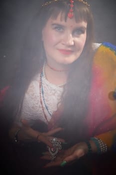 A mature woman poses gracefully in a vibrant sari, displaying intricate jewelry, capturing the essence of Indian fashion and culture.