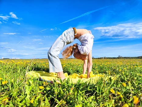 A joyful child showcases a yoga pose in a sunny meadow adorned with blooming flowers under a clear blue sky.
