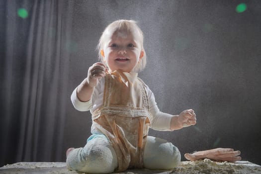 A girl explores the texture of flour while playing in a studio, showcasing a fun and creative cooking activity.