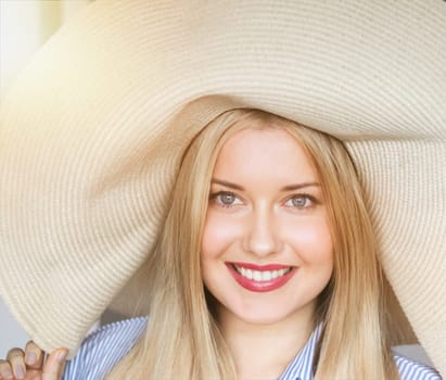 Woman, fashion and summer country charm, blonde beauty and elegance in wide brimmed beach hat. Feminine allure, timeless style and graceful glow. Smile, straw hat and blue striped blouse, natural lighting and effortless charm, fashion look idea