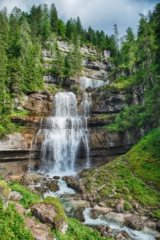 Water is cascading down the rocky mountainside at Vallesinella Falls in the Dolomites mountain range in Italy