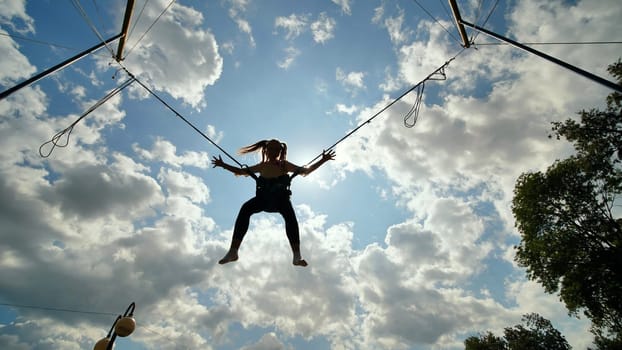 Teenage girl silhouette jumping on the trampoline bungee jumping