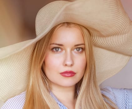 Woman, fashion and summer country charm, blonde beauty and elegance in wide brimmed beach hat. Feminine allure, timeless style and graceful glow. Smile, straw hat and blue striped blouse, natural lighting and effortless charm, fashion look idea