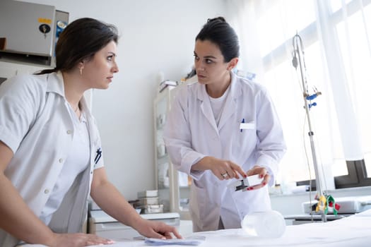 Two nurses in a hospital laboratory are carefully inspecting and preparing medications for patients and hospital use