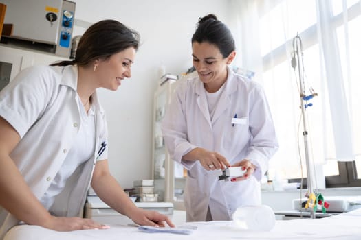 Two nurses in a hospital laboratory are carefully inspecting and preparing medications for patients and hospital use