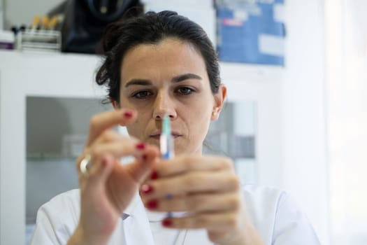 A focused nurse in a white lab coat carefully prepares a syringe for an injection in a professional healthcare environment