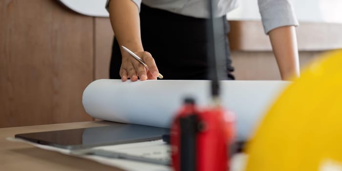 An architect prepares a large blueprint, emphasizing the attention to detail necessary in design. This image captures the dedication and focus required for successful project execution.