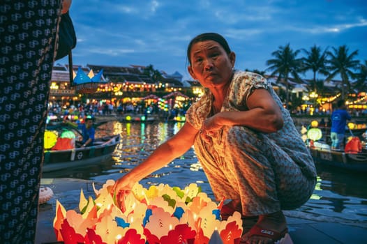 Old Vietnamese woman sells paper lanterns for a festive festival by river in old town in Hoi An in Asia. Hoi An, Vietnam - December 1, 2024