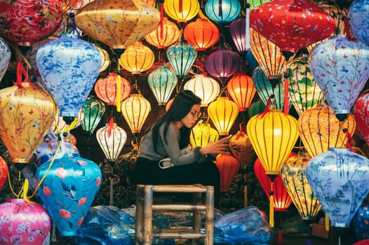 A young Vietnamese girl selling Chinese silk lanterns at Asian night market in Hoi An in Vietnam in Asia. Hoi An, Vietnam - December 1, 2024