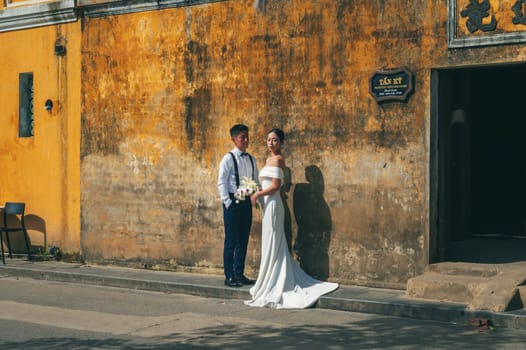 Vietnamese bride and groom. Asian couple in love at a wedding ceremony on street in the old town in Hoi An in Vietnam in Asia. Hoi An, Vietnam - December 1, 2024