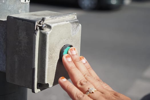 Individual touches pedestrian signal button to cross the street safely.