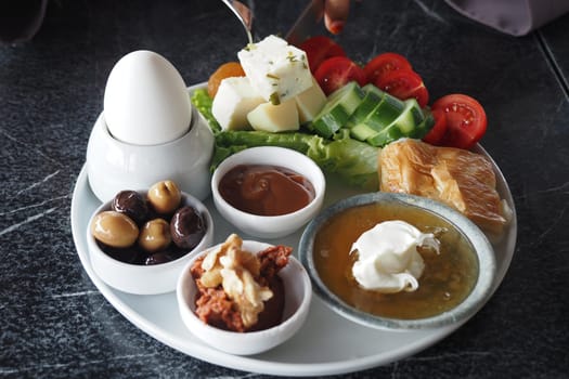 turkish breakfast spread features vegetables, cheese, and olives on a plate.