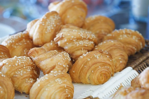Croissants topped with sesame seeds are beautifully arranged on a tray.