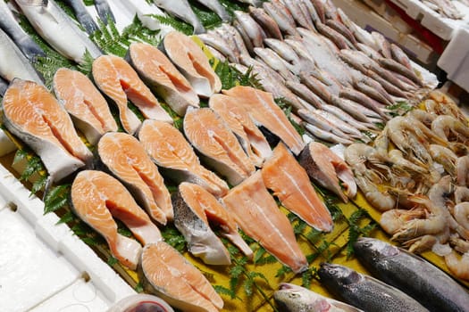 Fresh fish and shrimp laid out at a market stall during daytime.