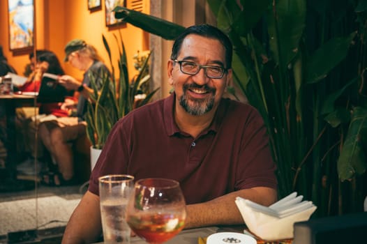 A happy, confident, successful adult Caucasian man is smiling and drinking wine while sitting at a table in restaurant. Da Nang, Vietnam - November 30, 2024