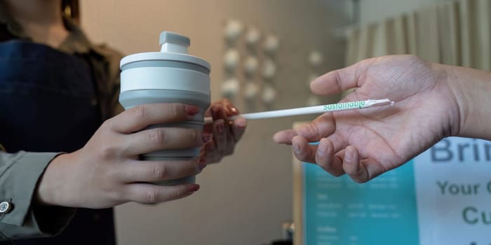 A customer is offered a sustainable straw along with their reusable cup, promoting eco-friendly dining choices and awareness.