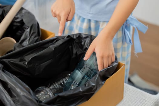A young child explores recycling by sorting plastic waste. The image captures their intent and curiosity in a home environment, fostering a sense of responsibility and environmental care.