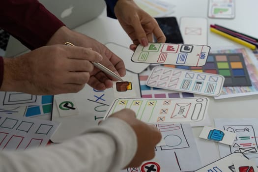 A group of designers collaborates on UX UI concepts, sharing sketches and feedback while holding various design prototypes in hands.