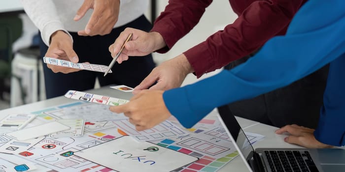 A diverse team of designers discussing and reviewing their UX design prototypes, showcasing creativity and teamwork in an interactive session.