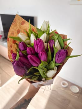 Tulip bouquet in hand with soft natural light and festive wrapping. Seasonal flower gifting and emotional expression at home