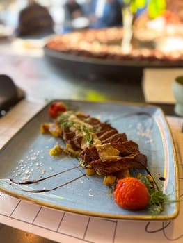 Gourmet beef steak with sauce and vegetables on ceramic plate in restaurant setting. Modern cuisine, flavor, and elegant food presentation