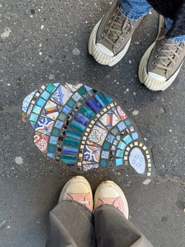 Two people standing by mosaic art on urban pavement. The image conveys the concept of spontaneous connection, artistic expression, and everyday beauty in city life