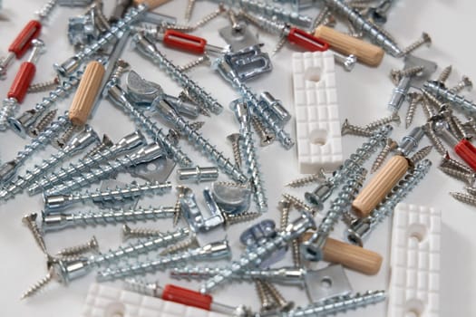 A variety of screws, bolts, and furniture hardware scattered on a white background. Ideal for concepts of assembly, repair, and home improvement