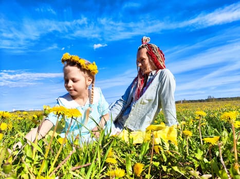 A joyful mother and daughter spend time together picking dandelions in a colorful field on a sunny day.