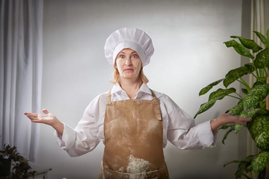 A funny photo shoot captures an elderly woman chef joyfully showcasing flour while cooking in her cozy kitchen.