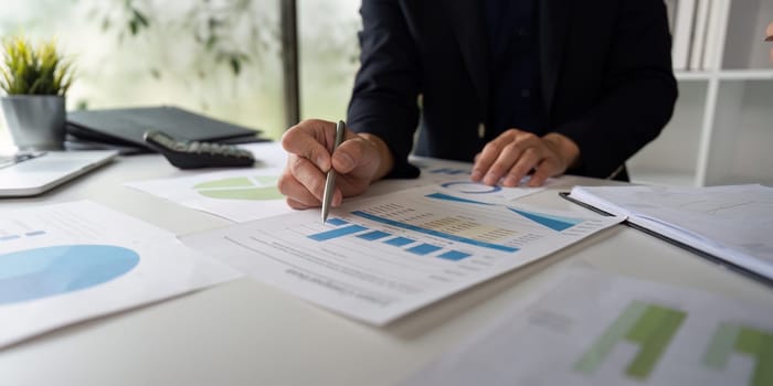 A business professional examines printed graphs and statistics, showcasing analytical skills to inform decision-making in a corporate environment.