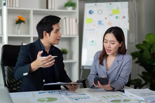 Two colleagues actively discuss financial graphics and insights while one gestures, demonstrating an interactive strategy planning session.