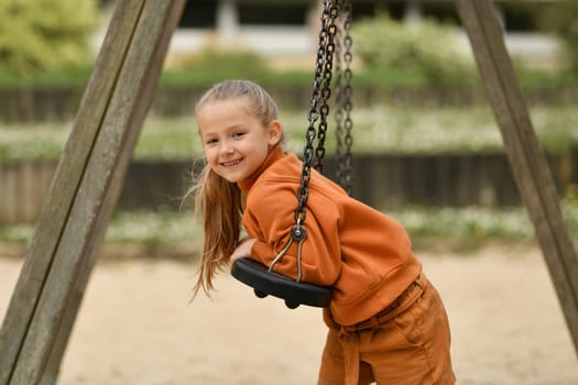 A girl riding on a swing in a park