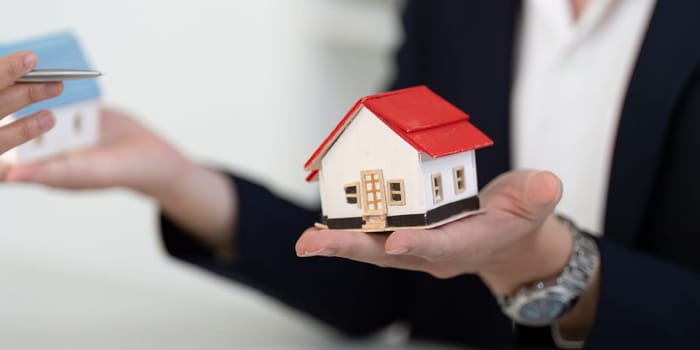 A professional real estate agent showcases a model home to a couple, highlighting features and discussing property options during a consultation.