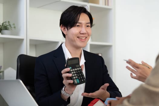 A friendly real estate agent engages in a conversation about property investment, showcasing the use of a calculator to clarify financial aspects.